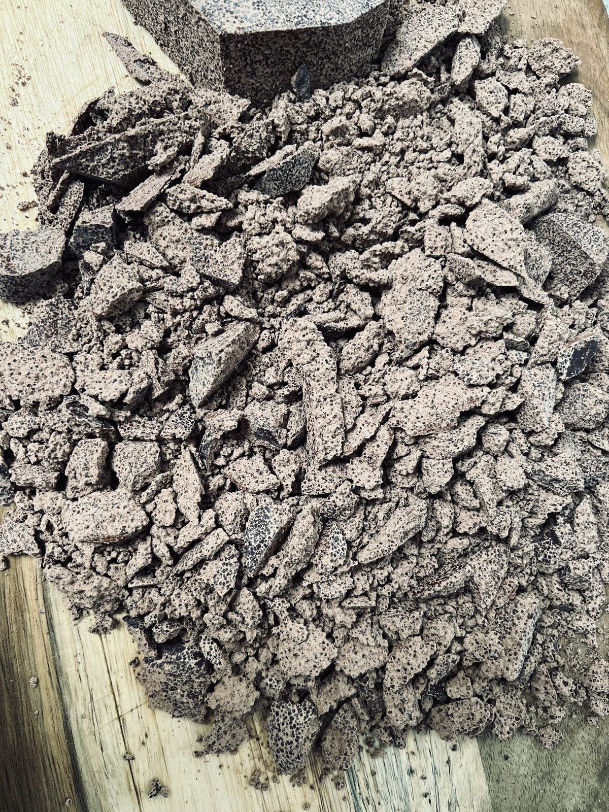 Broken chunks of stone-ground ceremonial cacao paste on a wooden board